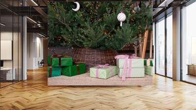 Close up of gift boxes under the christmas tree wihh wicker base. Christmas, New Year concept. Selective focus. Wall mural