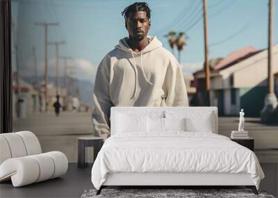 Confident young African man in a modern neutral colored tracksuit against a blurred background of a deserted street. Sports fashion and a sense of freedom Wall mural