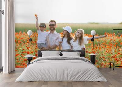 Happy family wearing white clothes hugging at the poppy field at sunrise. Mother, father, teen daughter and little son. Unity with nature, natural cosmetics, happiness concept. Selective focus. Wall mural