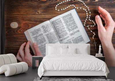 Open bible, candle, christian cross and human hands on wooden background. Prayer to God. Wall mural