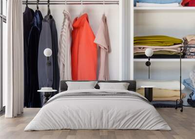 Shelves with colorful clothes in a white wardrobe close-up, minimalism style Wall mural