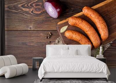 Smoked sausage with spices and onion on wooden background. Wall mural