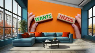 Wants and Needs symbol. Concept word Wants and Needs on wooden blocks. Businessman hand. Beautiful orange background. Business and Wants and Needs concept. Copy space Wall mural