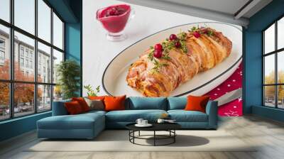 Cold appetizer, whole baked turkey and minced meat roll wrapped in bacon, on a white plate against a light concrete background. Wall mural