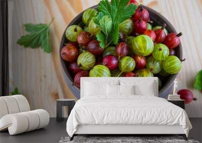 Red and green gooseberries in a ceramic bowl on a light wooden background. Cooking ingredients. Wall mural