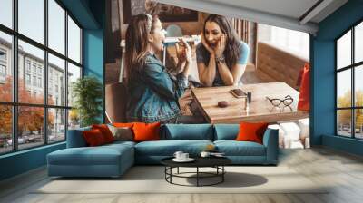 Cafes and bars. Two girls are sitting at a cafe table. Discussion of shopping. Joy and laughter. Girlfriends in a cafe. Wall mural