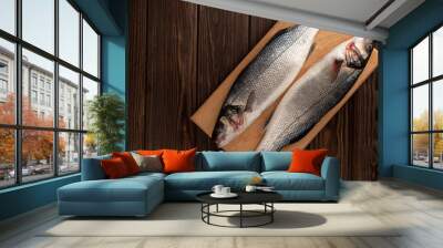 Two fresh sea bass fish on a cutting board, open space Wall mural