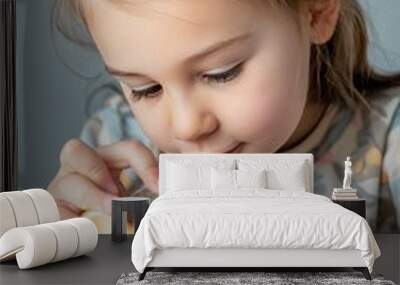 Young girl inserting a coin into a yellow piggy bank, focusing intently. The image captures the concept of saving money and financial education for children Wall mural