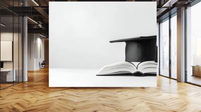 A mortarboard and graduation scroll on open books on whire background. education learning concept Wall mural