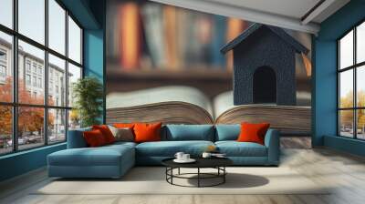 Miniature house on open book. On wooden table background Wall mural