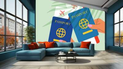 Two hands holding passport with plane tickets on green background with plant leaves  Wall mural