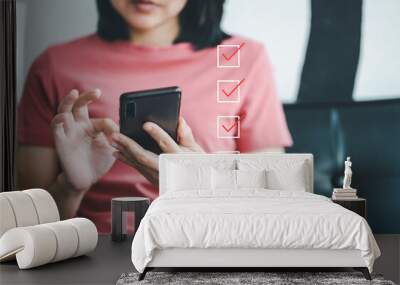 Woman holding smartphone and marking on checklist box with marker red. Customer service feedback on mobile. Wall mural