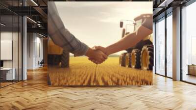 handshake of two men in shirts against the background of a mown field with yellow harvesters Wall mural