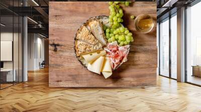 Appetizers antipasti with white sicilian focaccia. Traditional bread sliced cake with onion served with prosciutto ham, cheese, grapes and glass of white wine over wooden background. Flat lay, space Wall mural