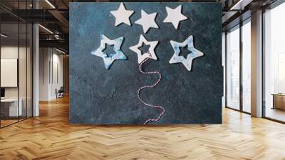 Christmas decoration ceramic stars white and blue glazed, different size, as christmas tree shape over blue texture background. Christmas and New year greeting card. Flat lay, space. Wall mural