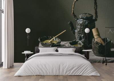 Japanese matcha green tea in craft ceramic cups with matcha powder, bamboo whisk, ceramic teapot on grey linen table cloth in dark room Wall mural