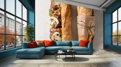 Opened and tied beef baguette sandwich with champignon mushrooms, green salad, fried onion over white marble background. Flat lay, space Wall mural