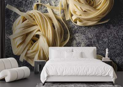 Variety of italian homemade raw uncooked pasta spaghetti and tagliatelle with semolina flour over black texture background. Flat lay, space Wall mural