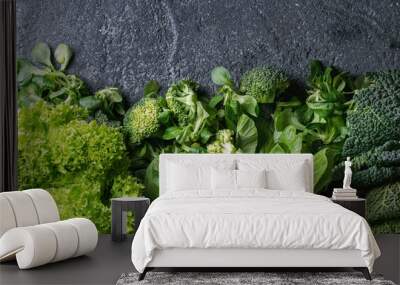 Variety of raw green vegetables salads, lettuce, bok choy, corn, broccoli, savoy cabbage as frame over black stone texture background. Top view, space for text Wall mural