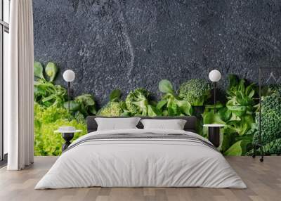 Variety of raw green vegetables salads, lettuce, bok choy, corn, broccoli, savoy cabbage as frame over black stone texture background. Top view, space for text Wall mural