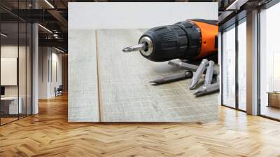 electric screwdriver, self-tapping screws, screwdriver bits, tool box on a wooden background Wall mural