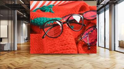 several different stylish eye glasses on a red knitted hat, christmas sale in the optics store Wall mural