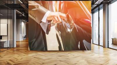 A man in a suit opens the door of a black car. Wall mural