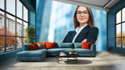 Young beautiful businesswoman in business suit smiling and looking at camera, female worker in glasses with crossed Wall mural