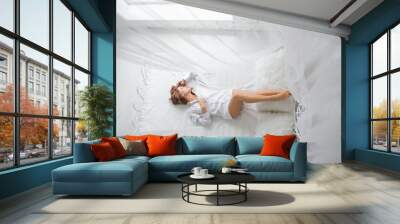 happy girl lies on a bed. Happy young woman lying on the bed with raised legs up. girl in a white men's shirt
 Wall mural