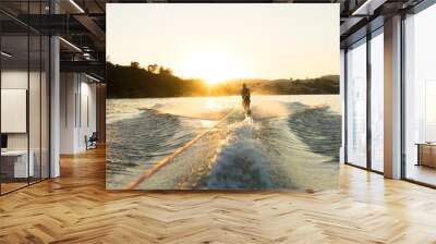 A water skier takes a run at sunset on a empty glassy lake Wall mural