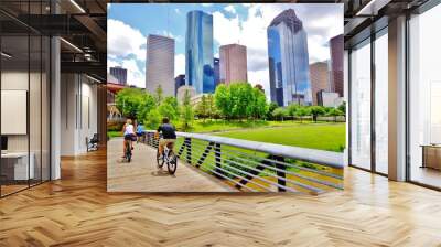 Bicyclists cross wooden bridge in Buffalo Bayou Park, with a beautiful view of downtown Houston (skyline / skyscrapers) in background on a summer day - Houston, Texas, USA  Wall mural