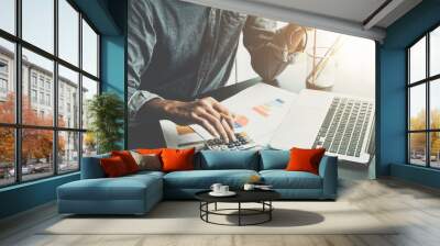 A man working about financial and analysis business document with calculator and holding glasses at his office to calculating expenses, Accounting concept Wall mural