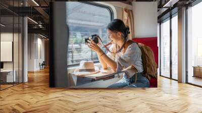 Beautiful Asian female tourist with sitting and take a photo travel location and sightseeing urban window view, public train transport, city lifestyle journey by railway Wall mural