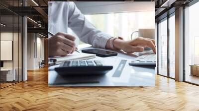 Business women using computer and calculator during note some data on notepad for calculate financial at home office Wall mural