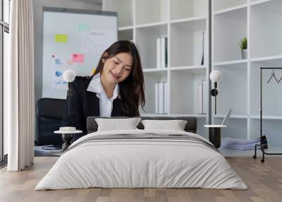 Charming Asian business woman sitting working on laptop in office Wall mural