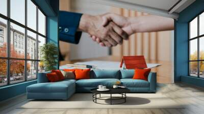 Estate agent shaking hands with his customer after contract signature, Contract document and house model on wooden desk Wall mural