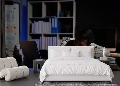 Exhausted businessman sleeping at his desk and working overtime late at night, he is surrounded by piles of paperwork Wall mural