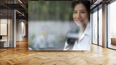 Portrait young asian business woman smile to you in the office, copy space, through the glass shot Wall mural