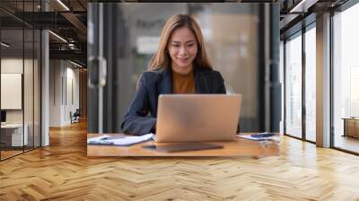 Smiling beautiful young asian woman working on laptop, business financial concept. Wall mural