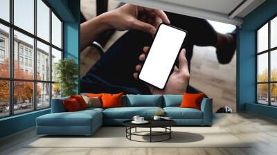 Top view male hand holding smartphone with blank screen at coffee shop Wall mural