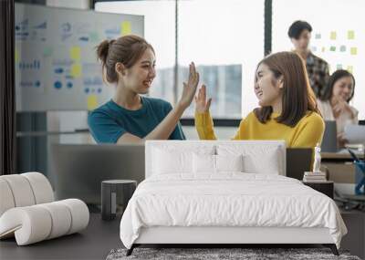 Young asian woman with modern laptop giving five to colleague partner in front after completed it startup project Wall mural