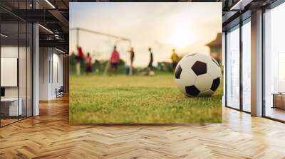 Action sport outdoors of kids having fun playing soccer football for exercise in community rural area under the twilight sunset sky. Picture with copy space. Wall mural