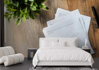 A stack of papers on a wooden table with a pen next to them Wall mural