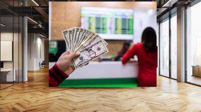 Young asian hand with money in cash department window at international airport,currency exchange concept. Wall mural