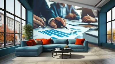 A focused business team analyzes financial charts and data during a strategic meeting, emphasizing collaboration and detailed planning.. Wall mural