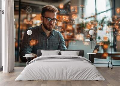 A man works on a laptop surrounded by glowing holographic data displays, representing modern technology and digital analytics... Wall mural