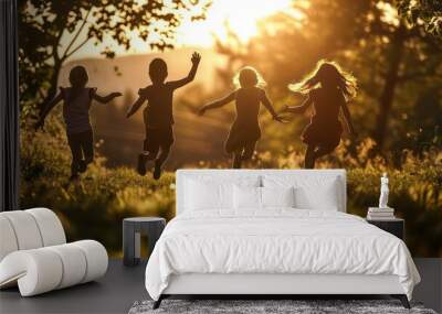 Four children joyfully leap and bound across the grassy park field, basking in the enchanting play of beautiful light and shadows. Wall mural