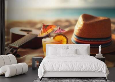  A glass of orange juice with cocktail umbrellas, a straw hat, and a ukulele rest on the sand with a blurry beach scene in the background. Beach relaxation, tropical vacation, enjoying the sunset. Wall mural