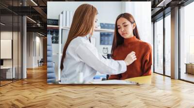 Asian doctor  examining young asian patient by using stethoscope at her chest Wall mural