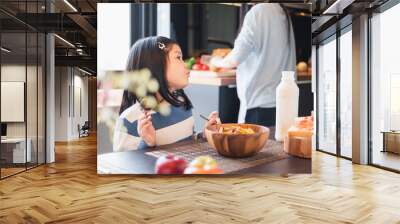 Asian girl kid having breakfast cereal at home kitchen Wall mural